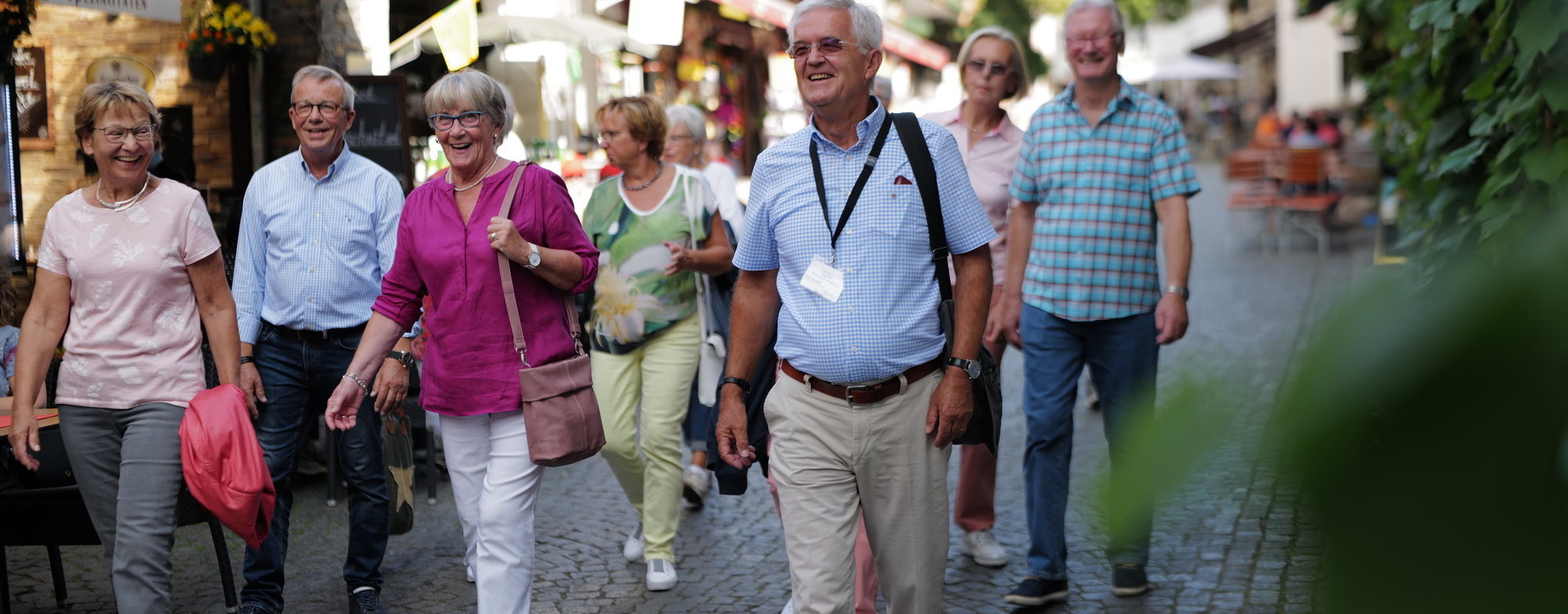 Stadtführung Rüdesheim Eine Gruppe mit vielen Personen geht durch die engen Straßen von Rüdesheim. Im Vordergrund geht der Stadtführer erkennbar an einem Ausweis um den Hals.