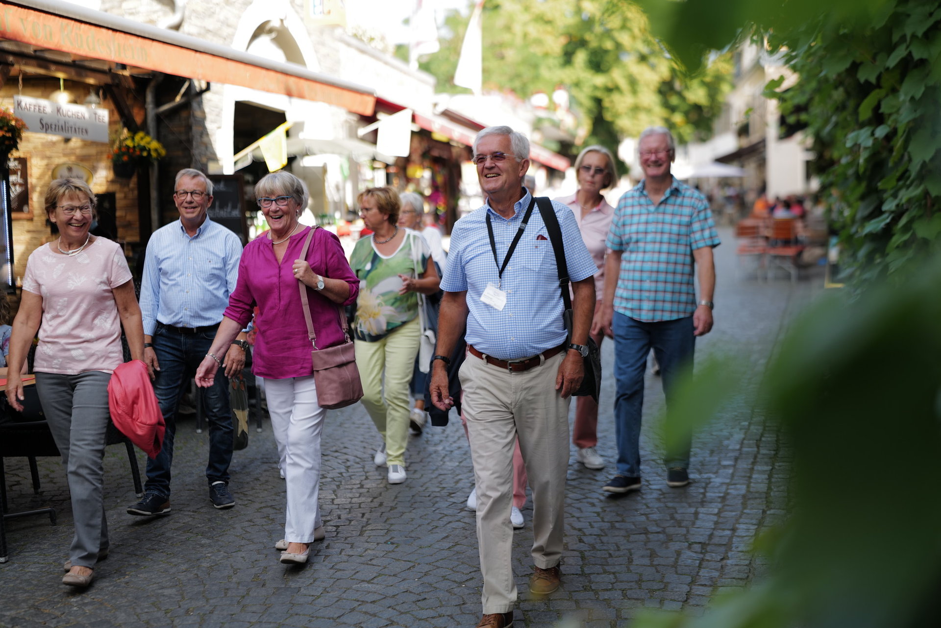 Stadtführung Rüdesheim Eine Gruppe mit vielen Personen geht durch die engen Straßen von Rüdesheim. Im Vordergrund geht der Stadtführer erkennbar an einem Ausweis um den Hals.