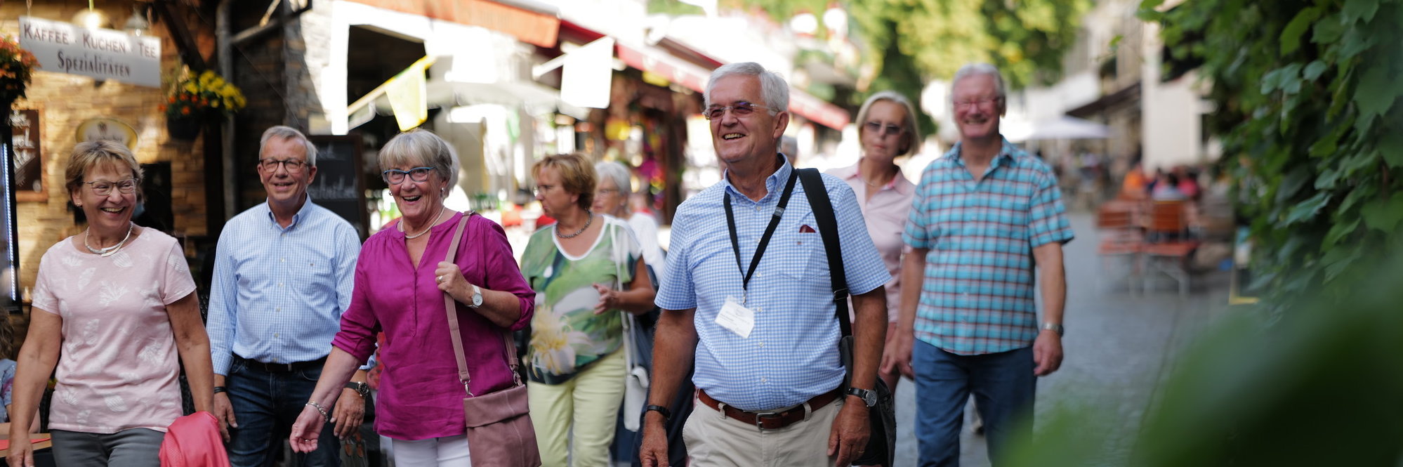 Stadtführung Rüdesheim Eine Gruppe mit vielen Personen geht durch die engen Straßen von Rüdesheim. Im Vordergrund geht der Stadtführer erkennbar an einem Ausweis um den Hals.