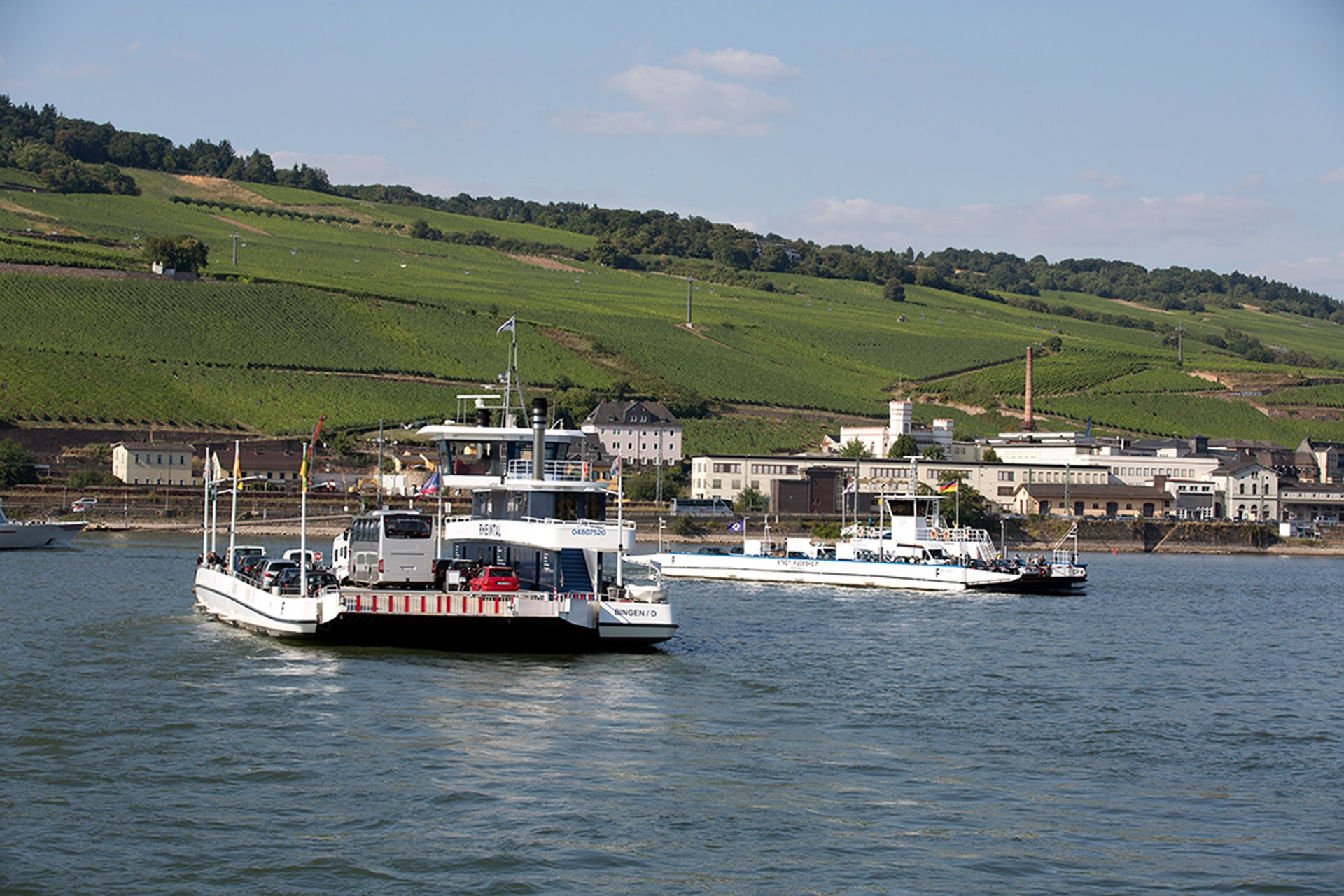 Zwei Autofähren kreuzen sich auf dem Rhein. Der Blick richtet sich auf die Rüdesheimer Weinberge