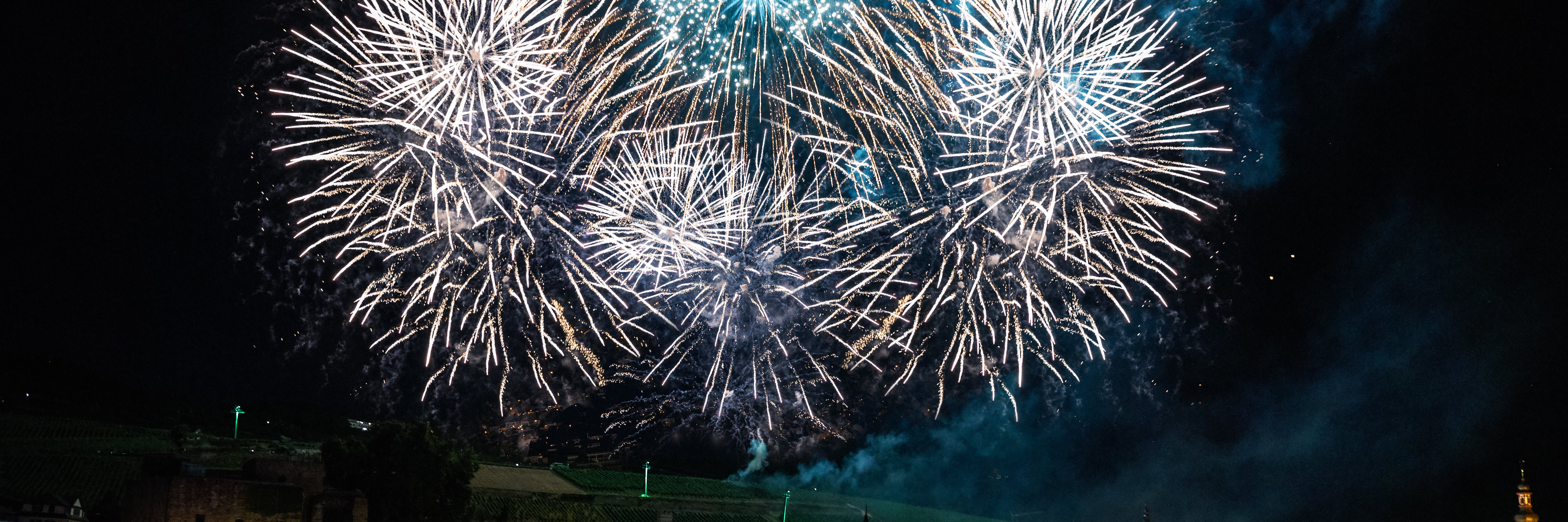 Feuerwerkskörper explodieren über der mit bunten farben beleuchtete Innenstadt von Rüdesheim