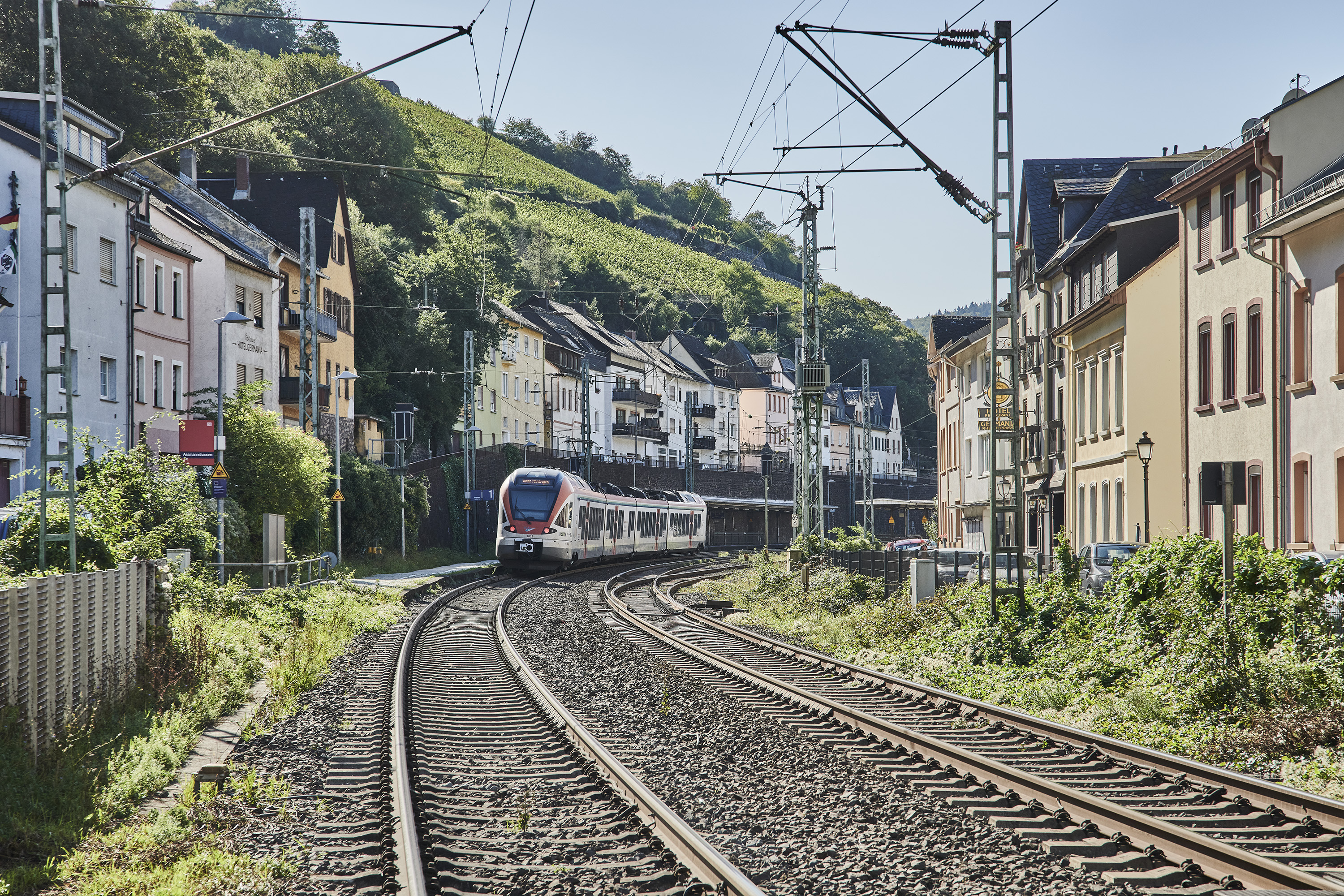 Ein Zug fährt auf den Gleisen durch einen Ort. Die Häuser sind eng an den Schienen gebaut.